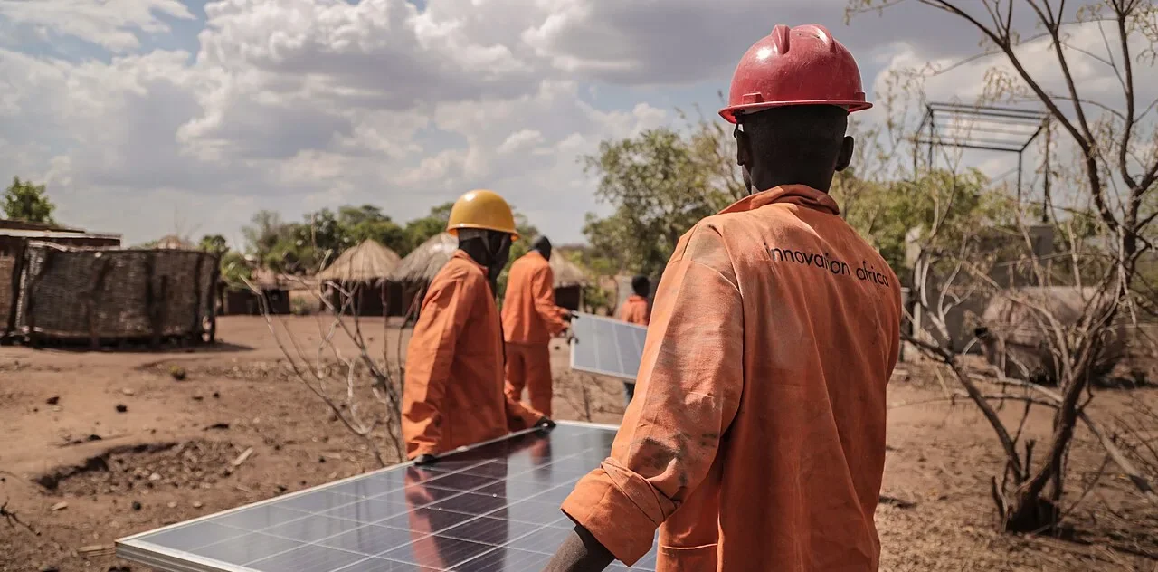 Des intervenants transportent des panneaux solaires dans une communauté rurale africaine